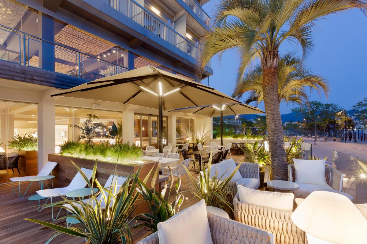 un restaurante con mesas y sillas blancas y una palmera en Hotel Maritim 4 Superior, en Roses