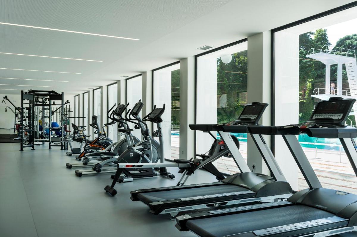 uma fila de máquinas de cardio num ginásio com janelas em Grande Hotel De Luso no Luso