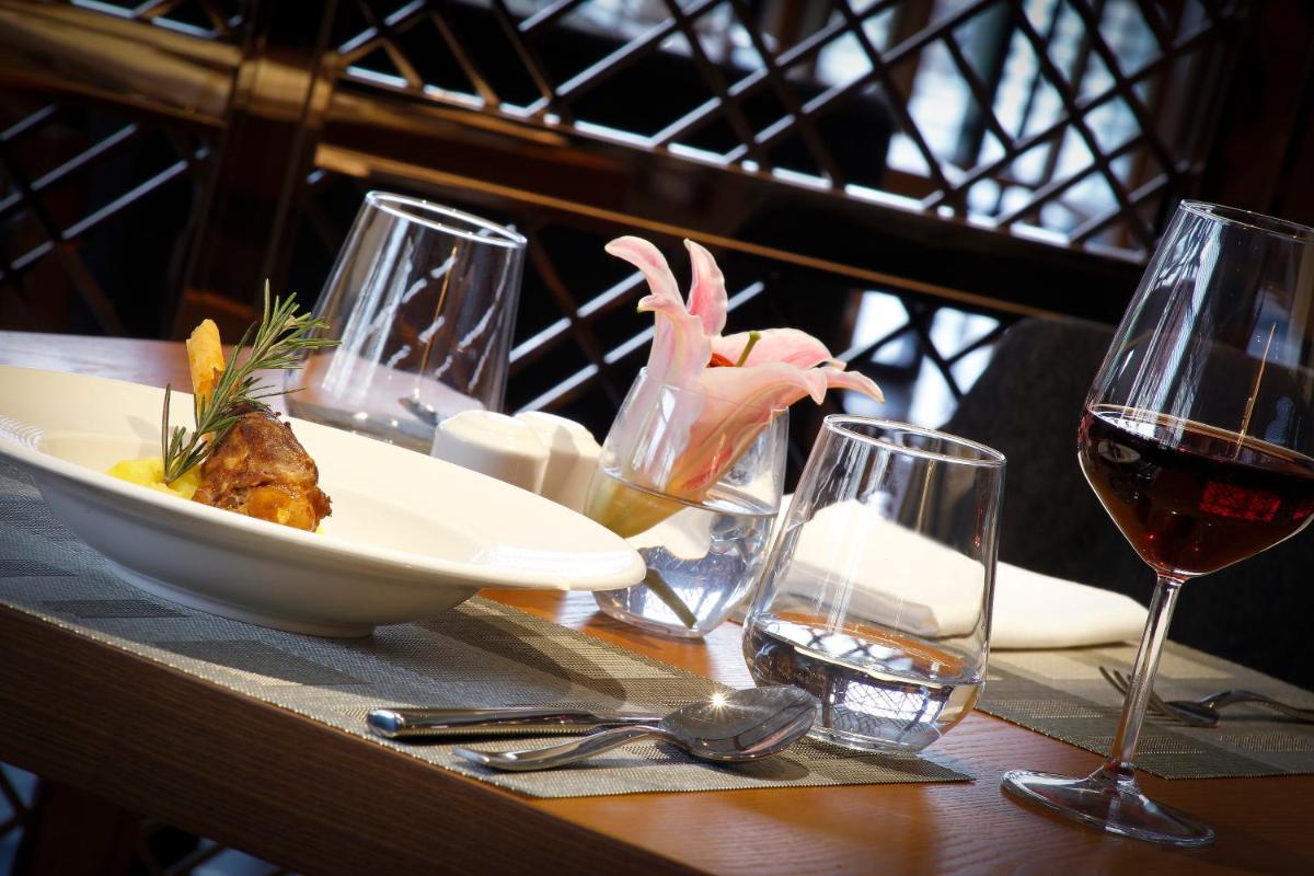 a table with a plate of food and glasses of wine at Novotel Chennai Chamiers Road in Chennai