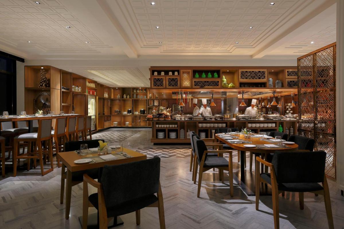 a restaurant with tables and chairs and a bar at Novotel Chennai Chamiers Road in Chennai