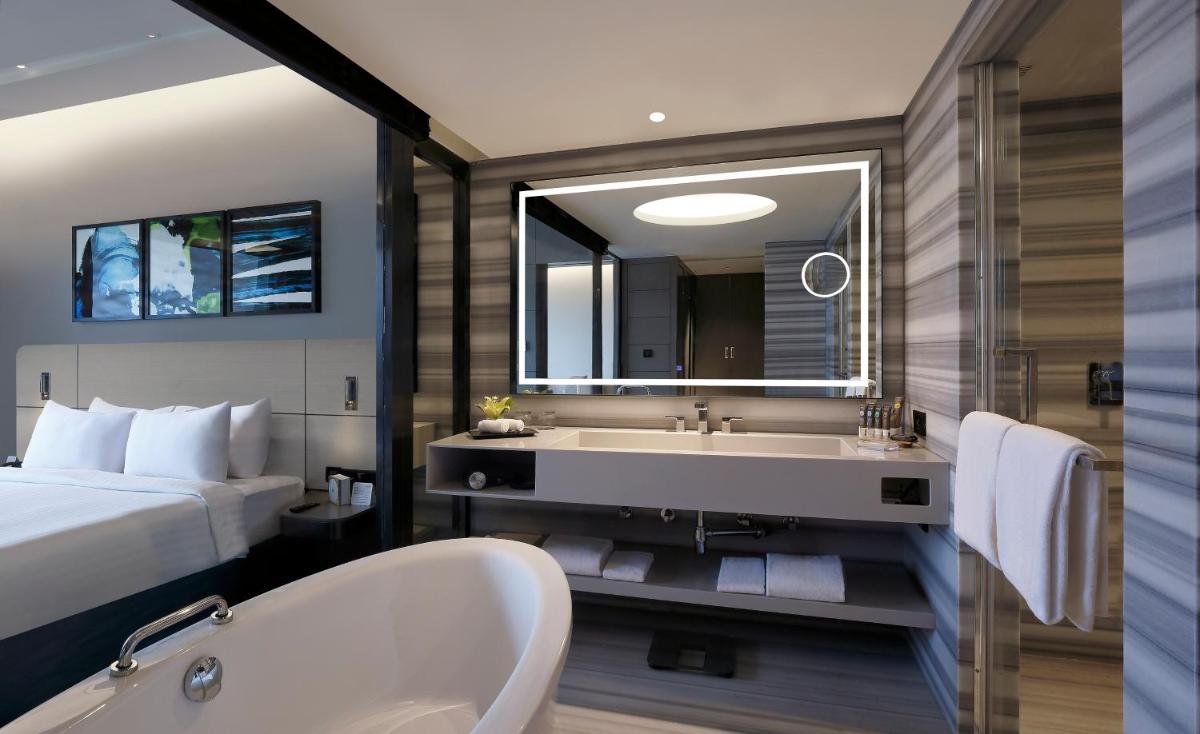 a bathroom with a bed and a bath tub and a bed and a bath tub at Novotel Chennai Chamiers Road in Chennai