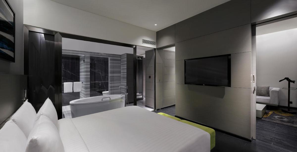 a bedroom with a bed and a flat screen tv at Novotel Chennai Chamiers Road in Chennai