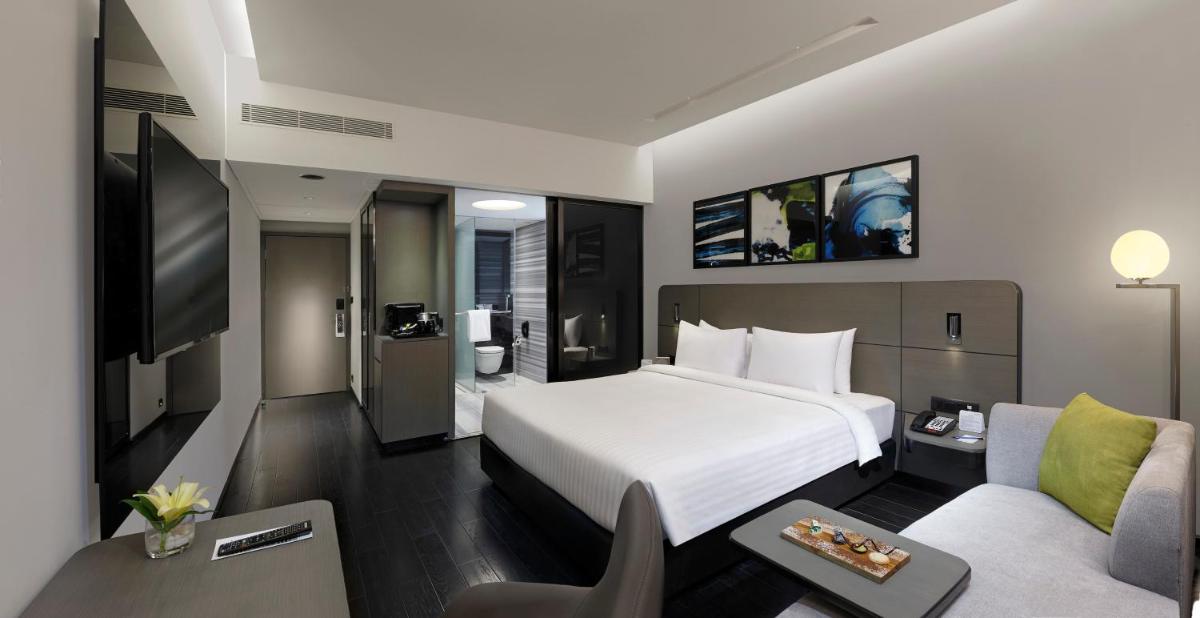 a hotel room with a bed and a couch at Novotel Chennai Chamiers Road in Chennai