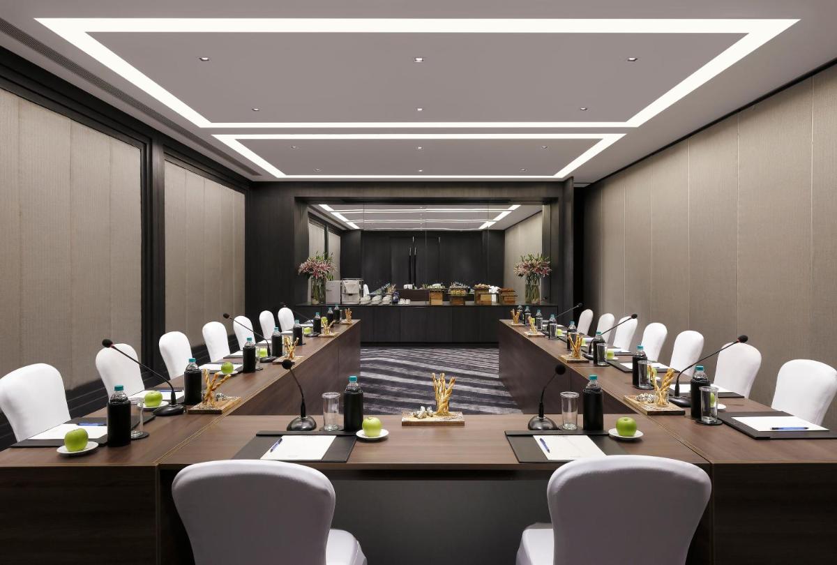 a large conference room with a long table and white chairs at Novotel Chennai Chamiers Road in Chennai