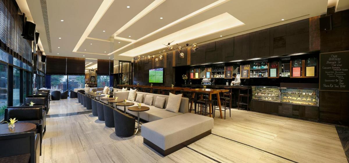 a restaurant with a bar with tables and chairs at Novotel Chennai Chamiers Road in Chennai