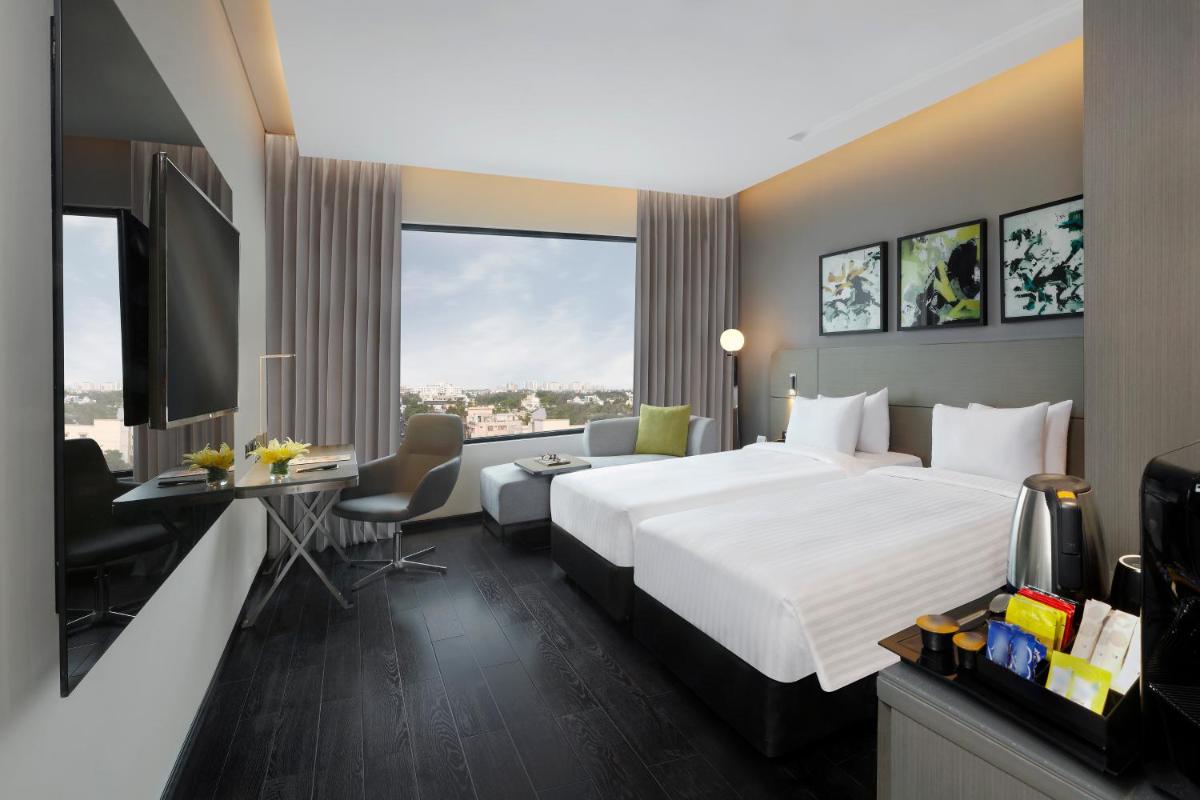 a hotel room with a large bed and a desk at Novotel Chennai Chamiers Road in Chennai