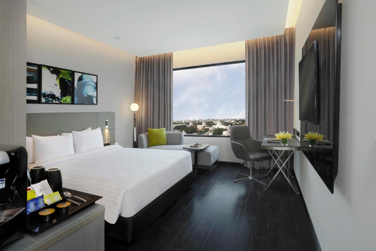 a hotel room with a large bed and a desk at Novotel Chennai Chamiers Road in Chennai