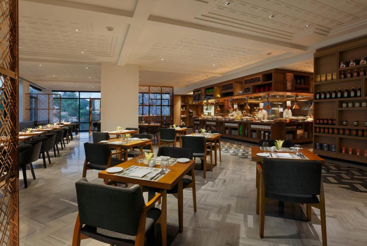 a restaurant with tables and chairs and a bar at Novotel Chennai Chamiers Road in Chennai