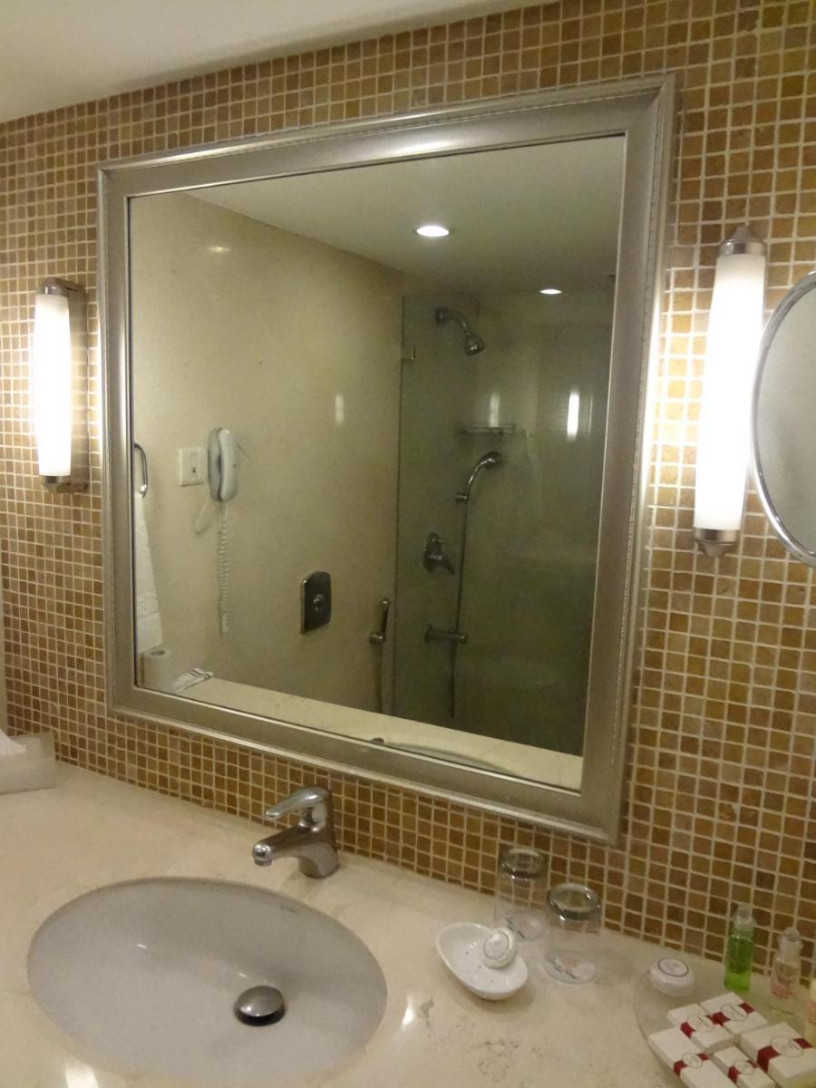 a bathroom with a sink with a mirror and a shower at Sun-n-Sand Mumbai Juhu Beach in Mumbai