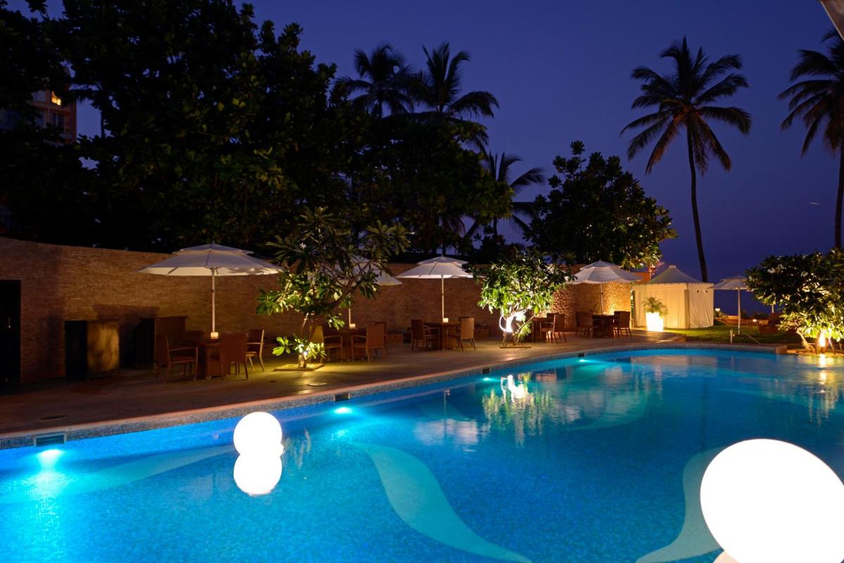 a swimming pool at night with tables and umbrellas at Sun-n-Sand Mumbai Juhu Beach in Mumbai