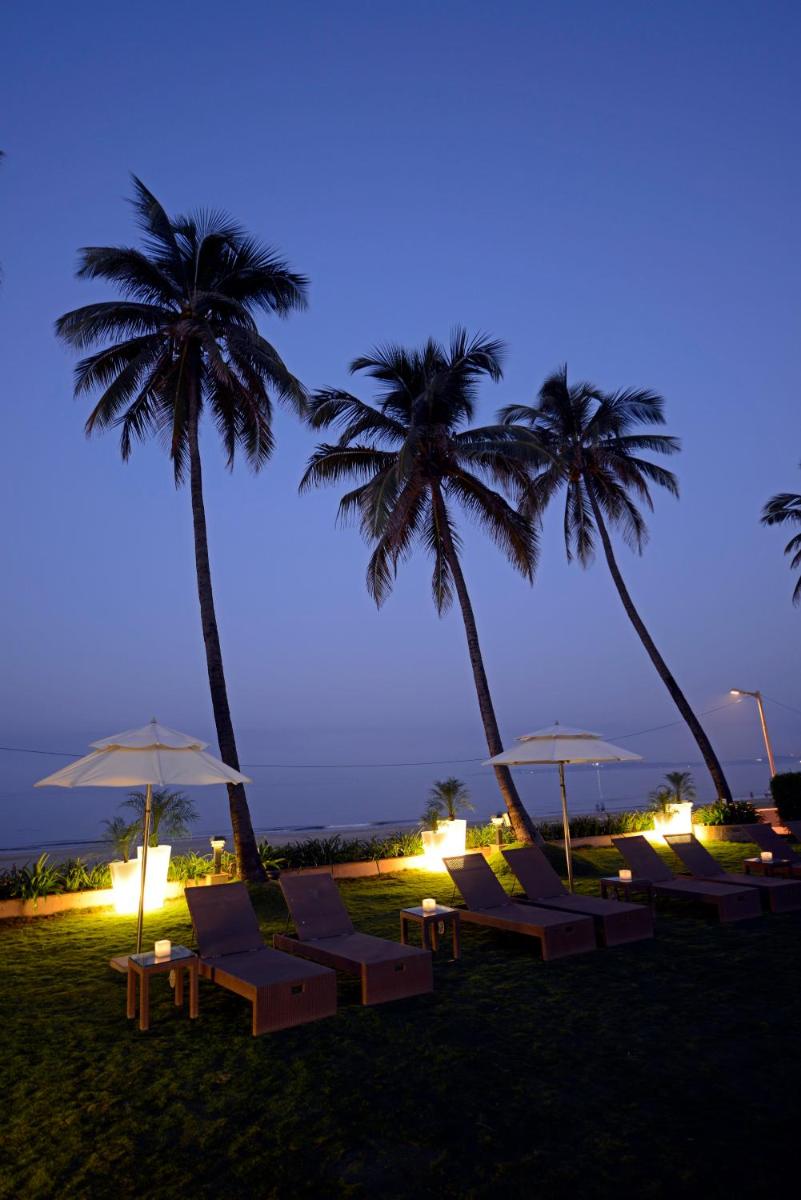 a group of lounge chairs and palm trees at night at Sun-n-Sand Mumbai Juhu Beach in Mumbai
