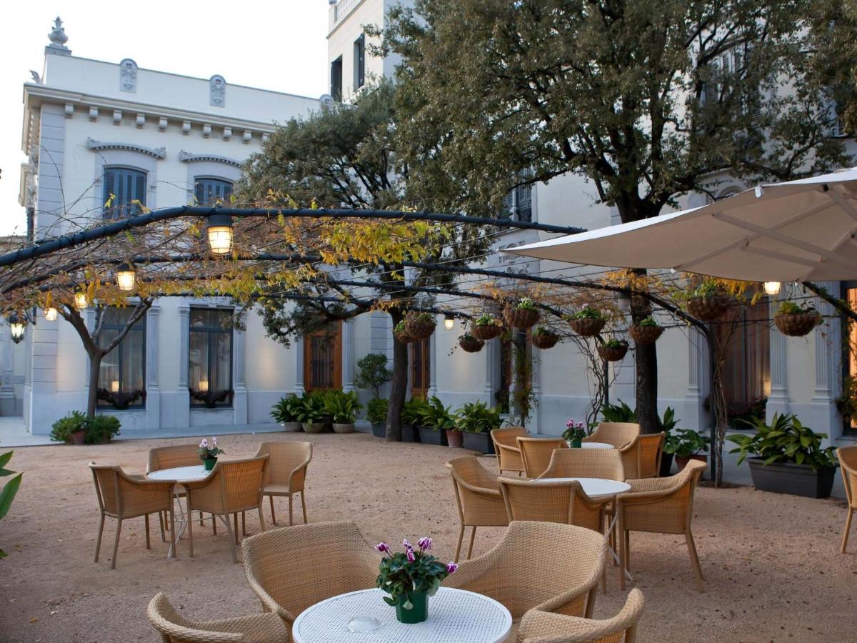 Un patio al aire libre con mesas, sillas y una sombrilla. en Hotel Balneario Prats, en Caldes de Malavella