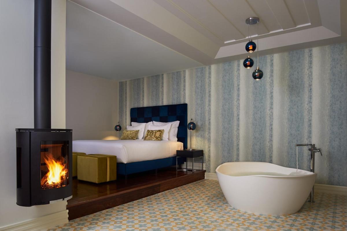 um quarto com uma banheira, uma cama e uma lareira em Convento do Seixo Boutique Hotel & Spa no Fundão
