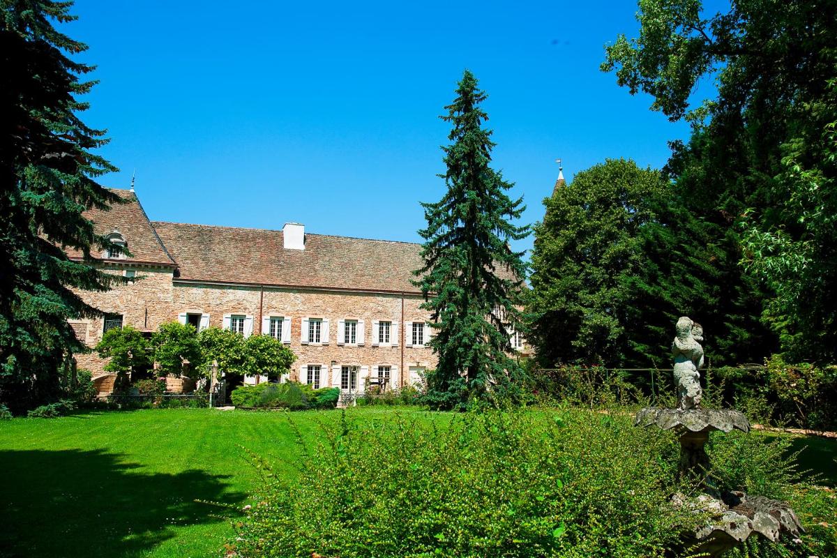 - un grand bâtiment en briques avec une statue devant dans l'établissement Château de Fleurville & Spa, à Fleurville