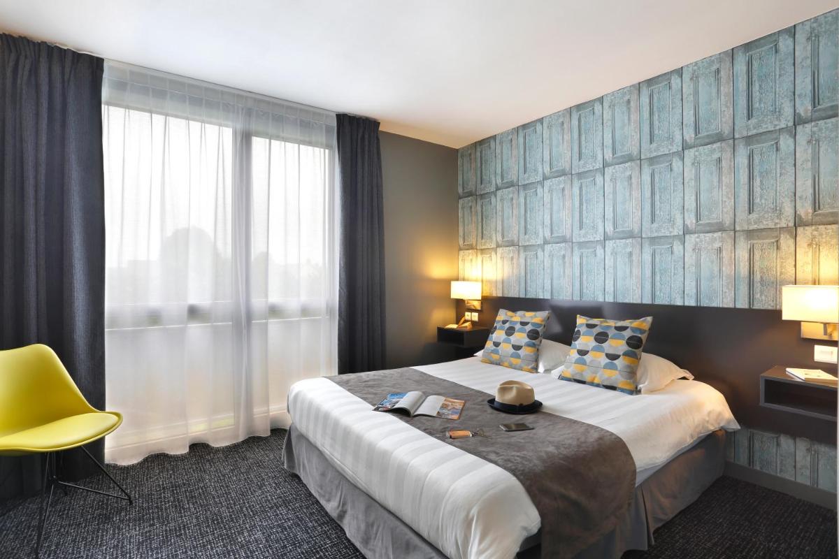 une chambre d'hôtel avec un grand lit et une chaise jaune dans l'établissement Altos Hotel & Spa, à Avranches 38 autres photos