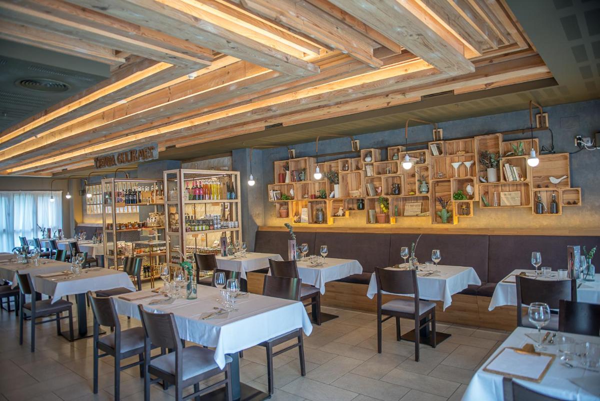 un restaurante con mesas blancas, sillas y libros en Apartahotel & Spa Jacetania, en Jaca