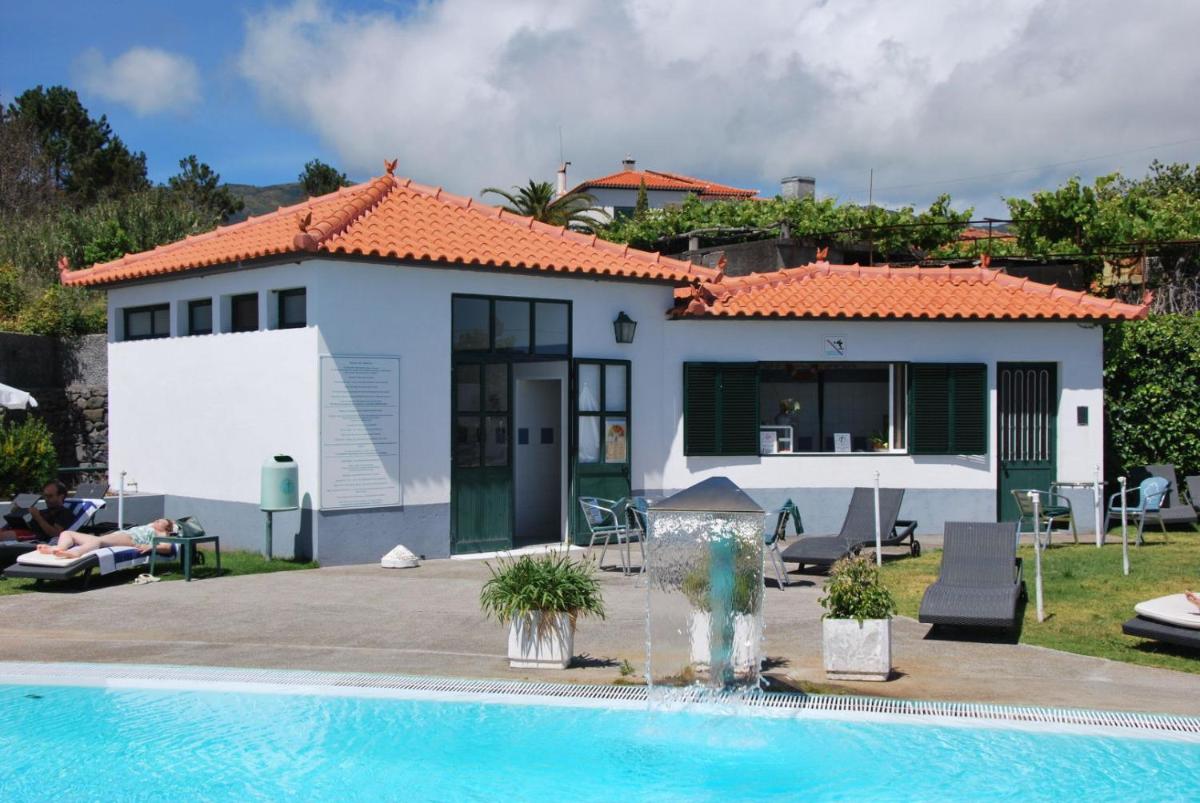 uma casa com piscina na frente de uma casa em Hotel Jardim Atlantico na Calheta