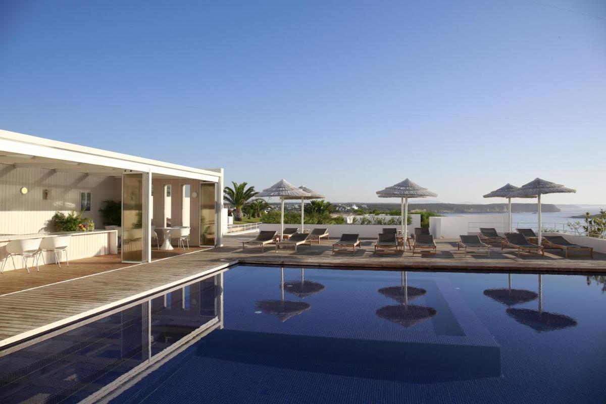uma piscina com cadeiras e guarda-sóis em um prédio em Memmo Baleeira - Design Hotels em Sagres