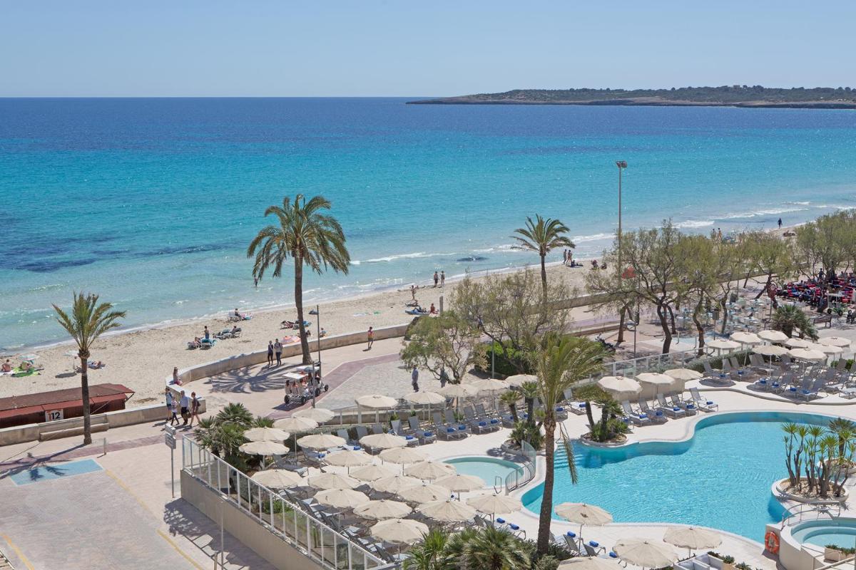 Una vista de la playa desde el balcón de un resort. en Hotel Sabina, en Cala Millor