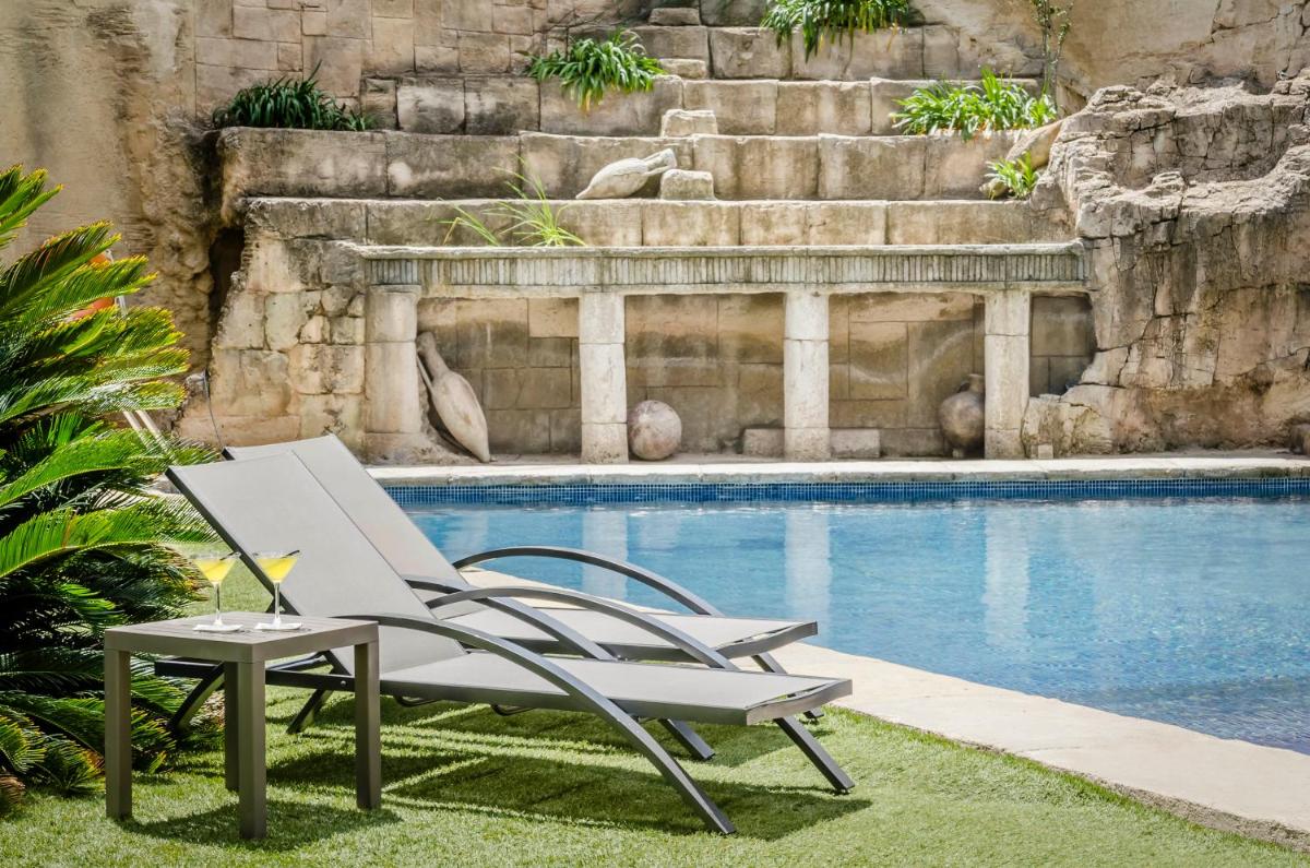 una silla y una mesa junto a la piscina en Exe Cunit Suites & Spa, en Cunit