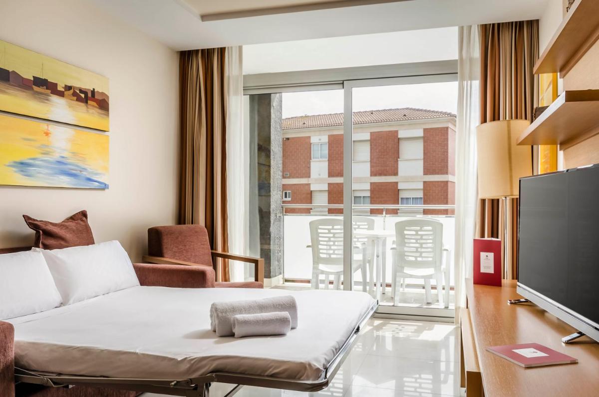 Una sala de estar con un sofá y un televisor. en Exe Cunit Suites & Spa, en Cunit