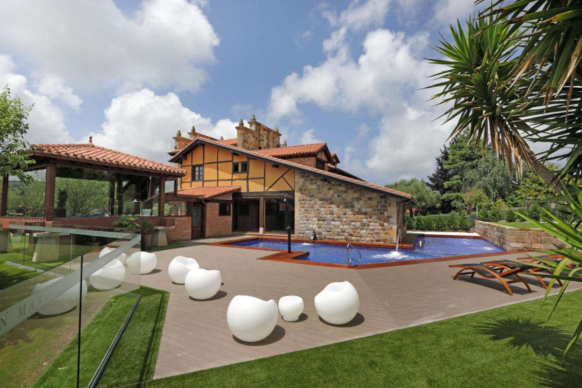 una casa con piscina y sillas blancas en el patio en Hotel Spa San Marcos, en Santillana del Mar