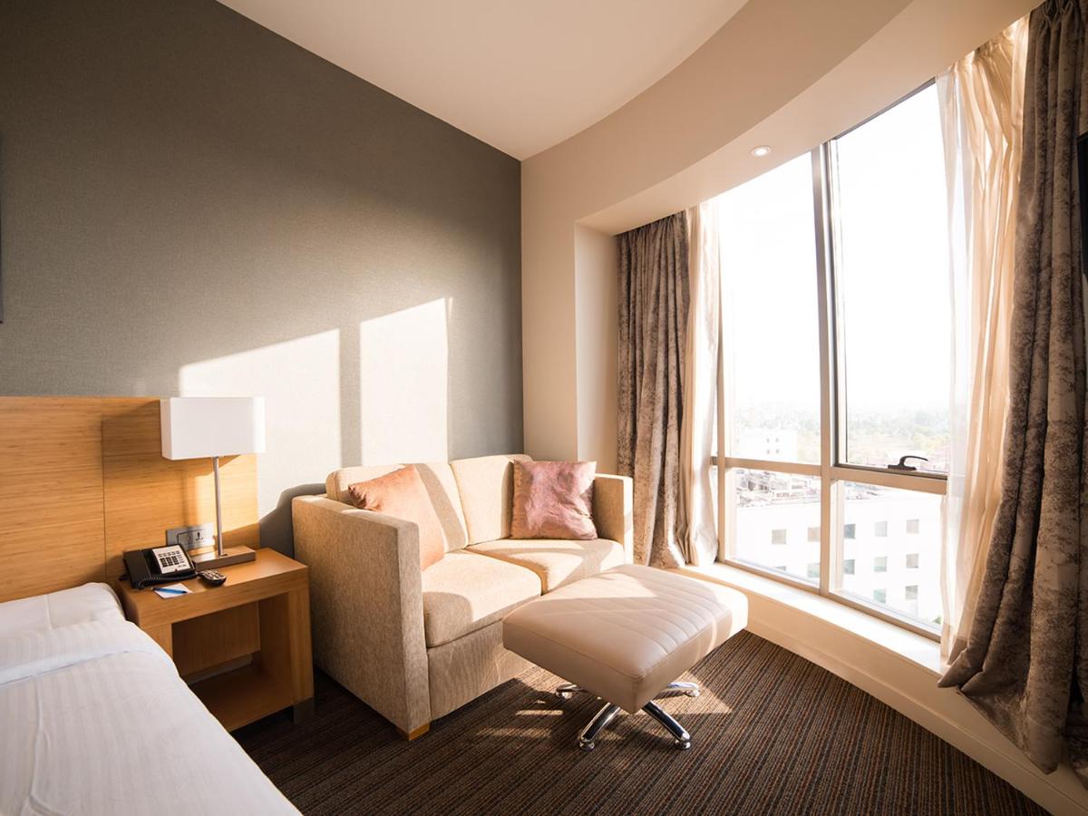 a hotel room with a chair and a window at Novotel Lucknow Gomti Nagar in Lucknow
