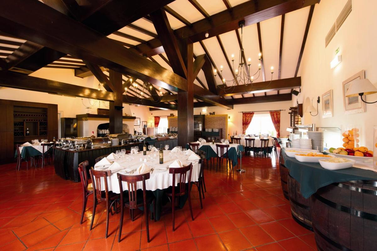 um restaurante com mesas e cadeiras brancas e um buffet em Vila Gale Alentejo Vineyard - Clube de Campo em Albernoa