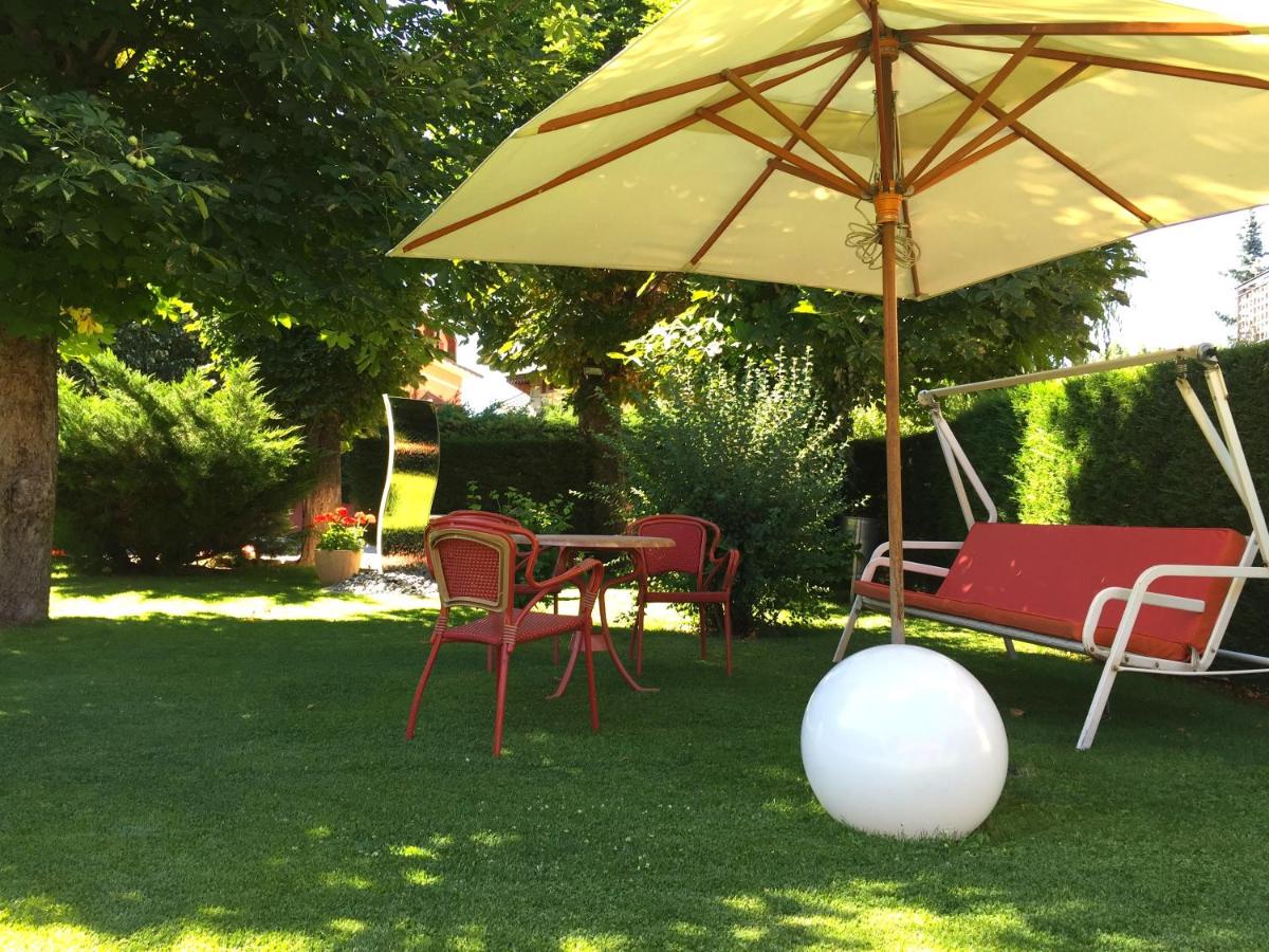 Una mesa y sillas con una sombrilla en el césped. en Hotel Del Lago, en Puigcerdà