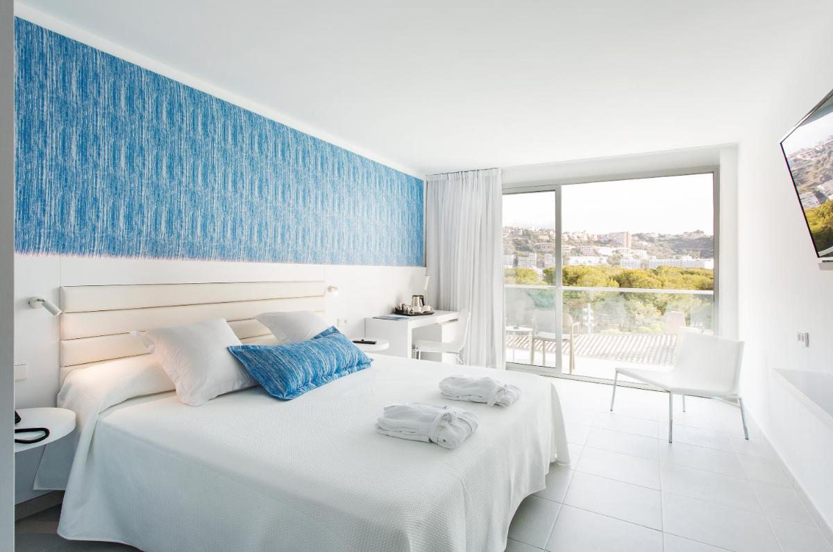 Un dormitorio con una cama blanca con una pared azul. en Reverence Life Hotel - Adults Only, en Santa Ponsa