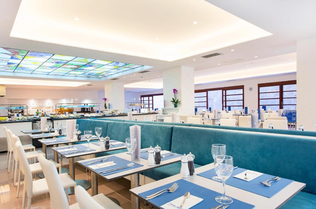 Una fila de mesas en un restaurante con un banco azul. en Reverence Life Hotel - Adults Only, en Santa Ponsa
