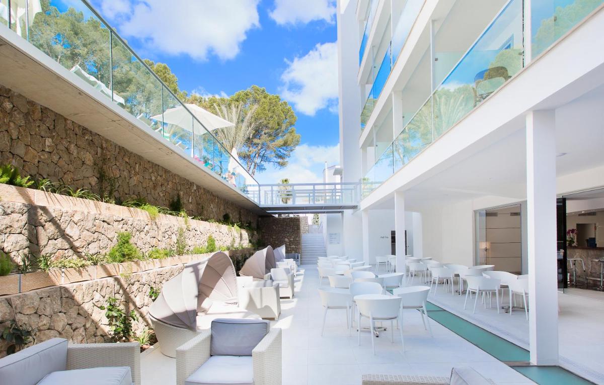 un restaurante con sillas blancas y una pared de piedra en Reverence Life Hotel - Adults Only, en Santa Ponsa