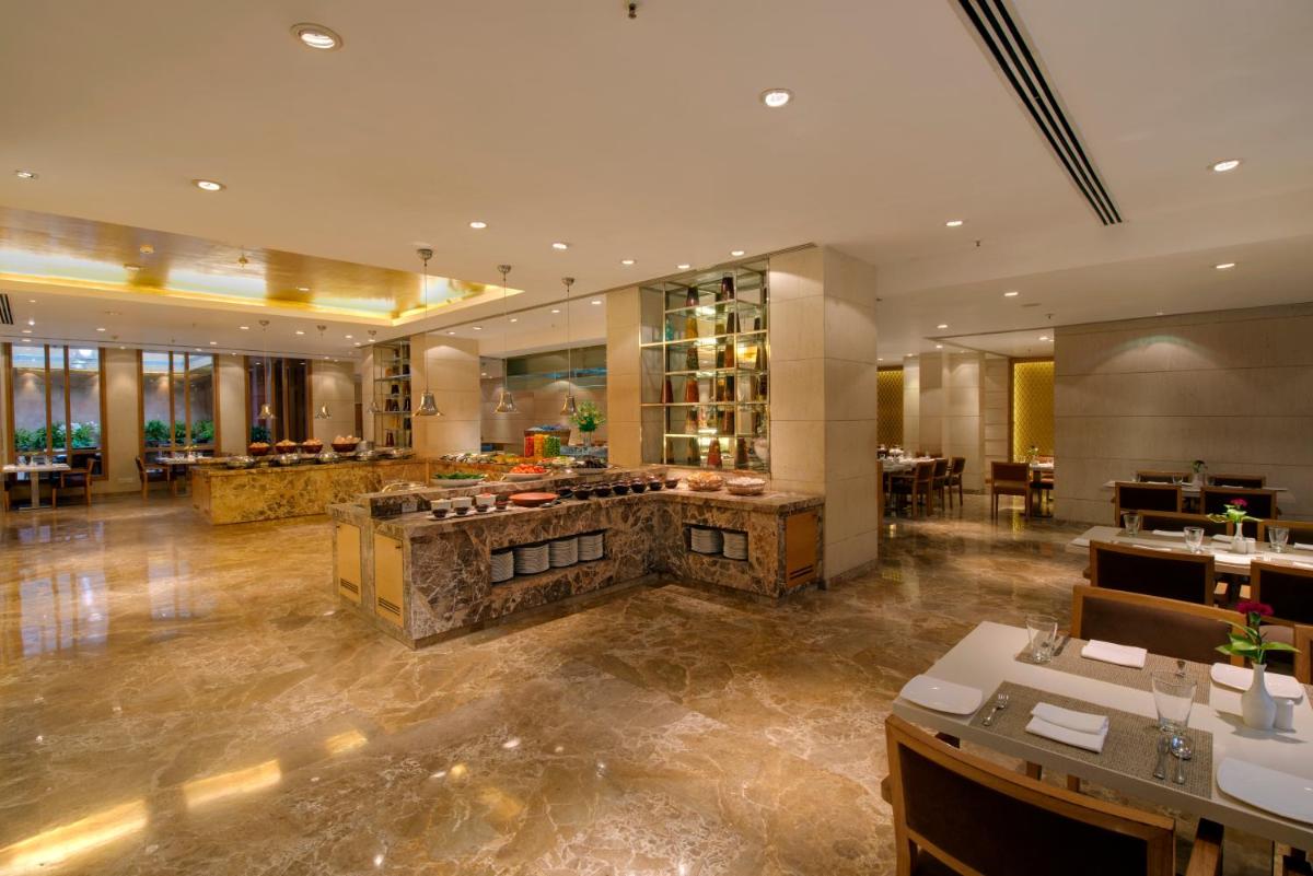 a restaurant with a large lobby with tables and chairs at Jaypee Palace Hotel in Agra