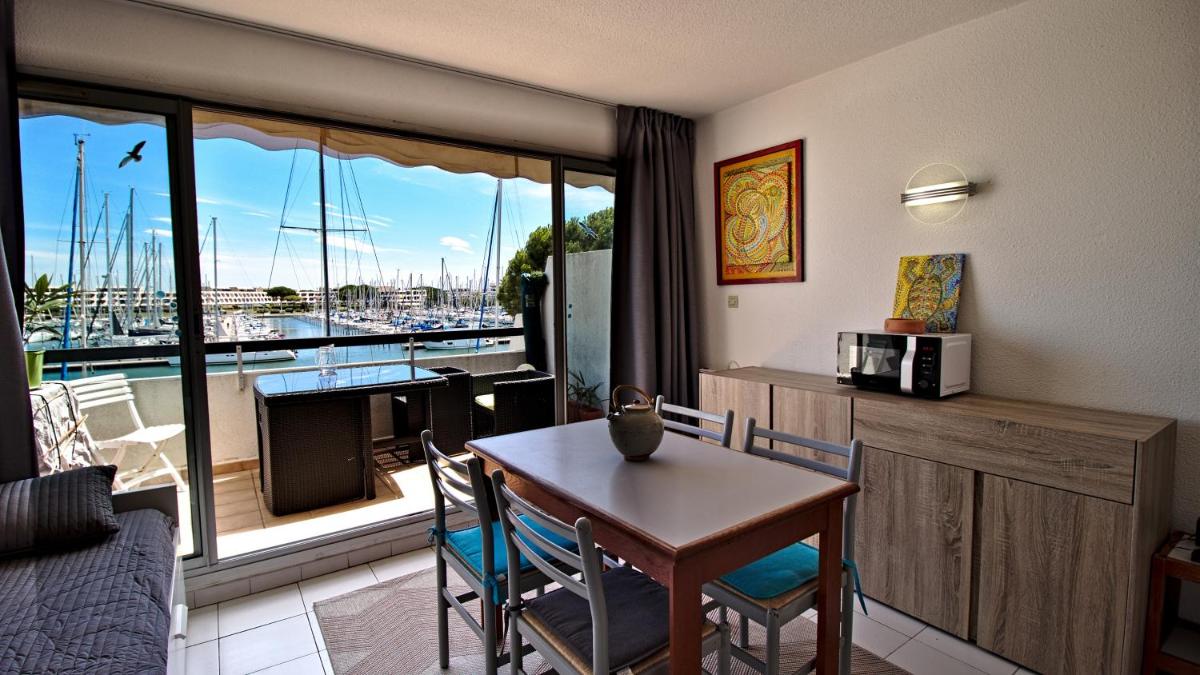 un salon avec une table et une vue sur un port de plaisance dans l'établissement Rivages d'Ulysse Port Camargue, au Grau-du-Roi