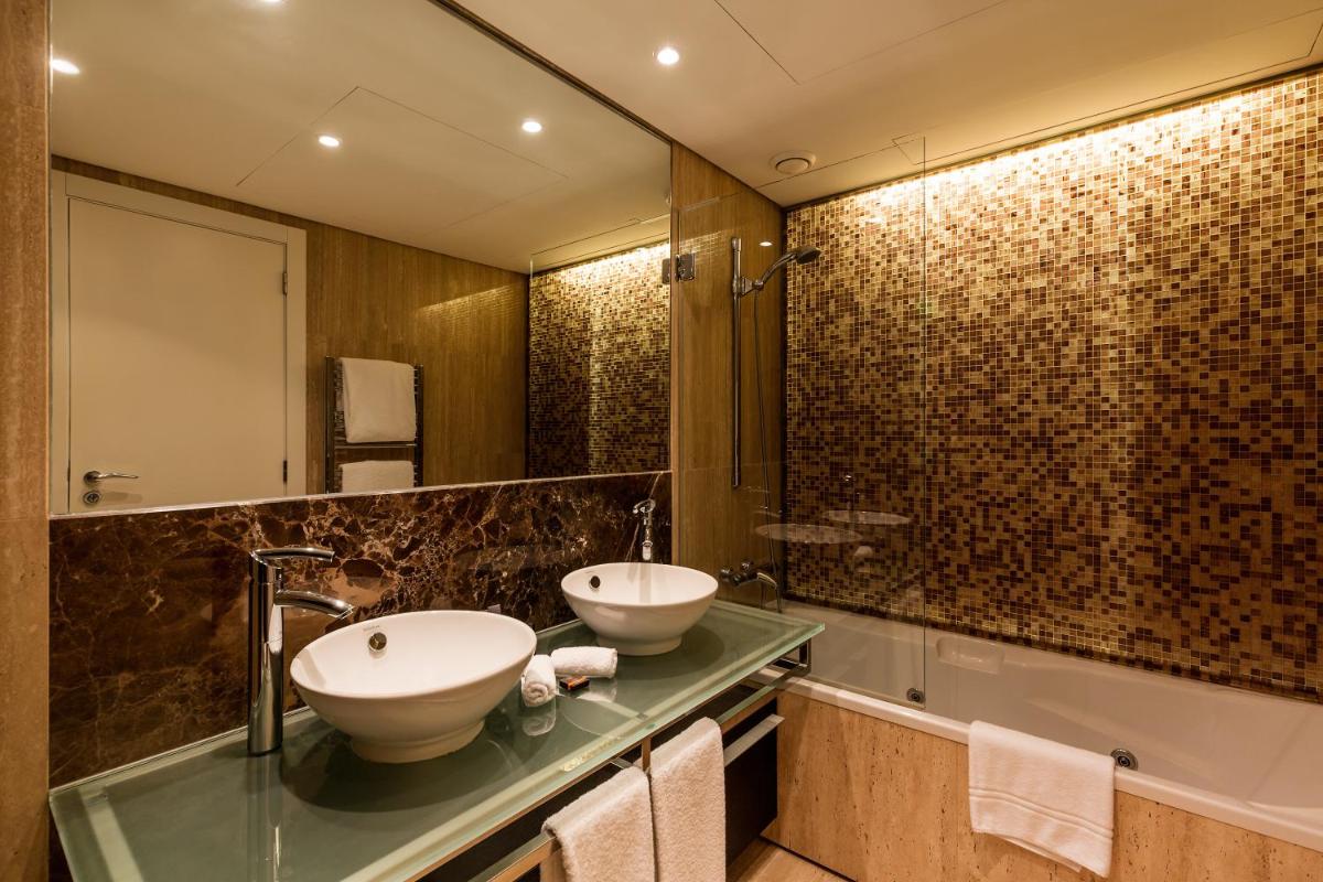 uma casa de banho com 2 lavatórios, um espelho e uma banheira em As Cascatas Golf Resort & Spa em Vilamoura