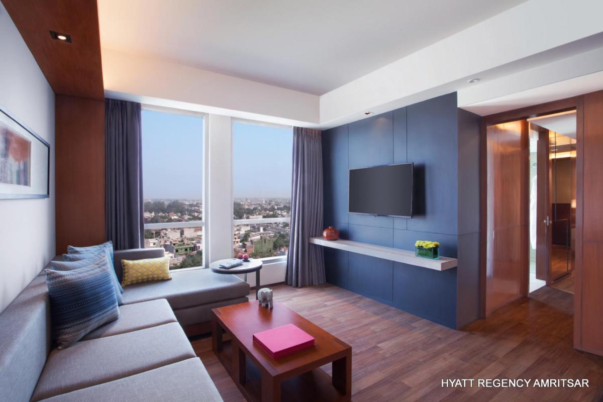 a living room with a couch and a tv at Hyatt Regency Amritsar Hotel & Spa in Amritsar