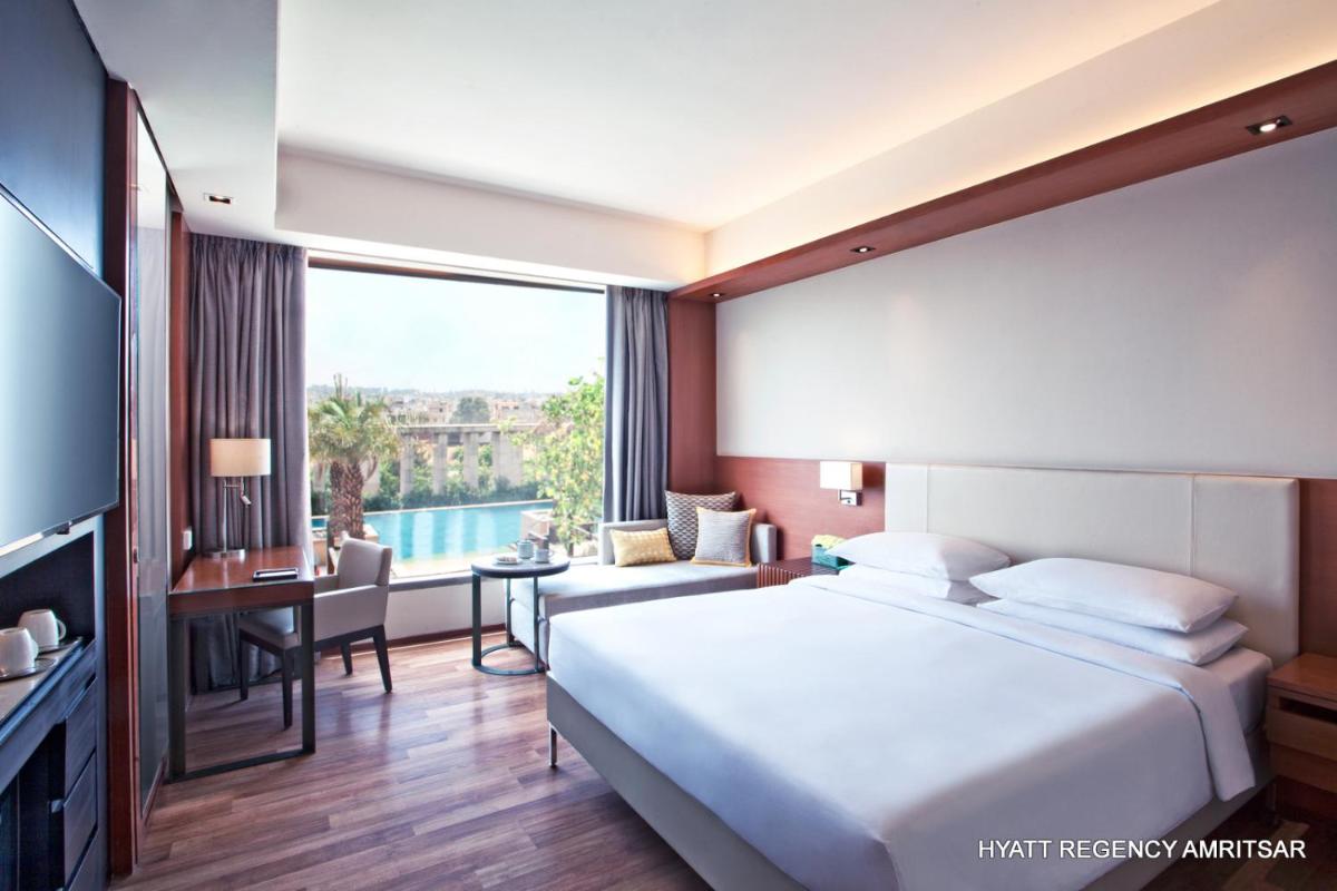 a hotel room with a large bed and a desk at Hyatt Regency Amritsar Hotel & Spa in Amritsar