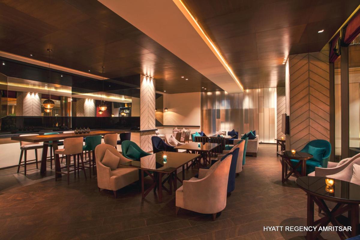 a restaurant with tables and chairs and a bar at Hyatt Regency Amritsar Hotel & Spa in Amritsar