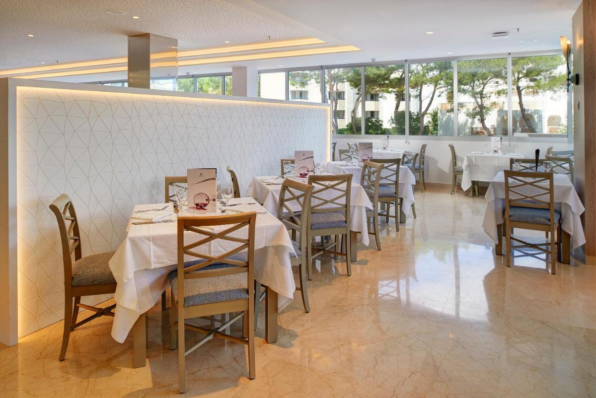 Un restaurante con mesas y sillas con mantel blanco. en Hipotels Bahia Cala Millor - Adults Only, en Cala Millor