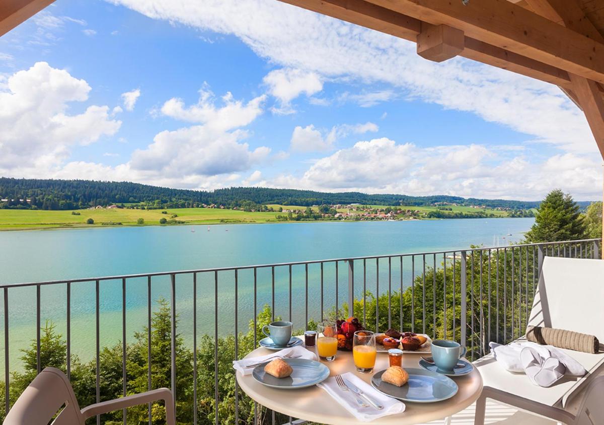 - une table avec de la nourriture sur un balcon avec vue sur le lac dans l'établissement Hotel Spa Les Rives Sauvages, à Malbuisson