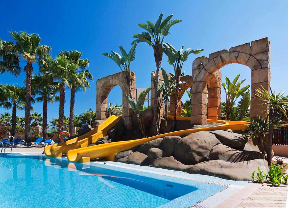 una piscina en un resort con toboganes y palmeras en Playacanela, en Isla Canela