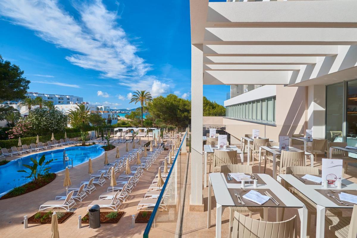 un restaurante con mesas y sillas blancas y una piscina en Hipotels Bahia Cala Millor - Adults Only, en Cala Millor