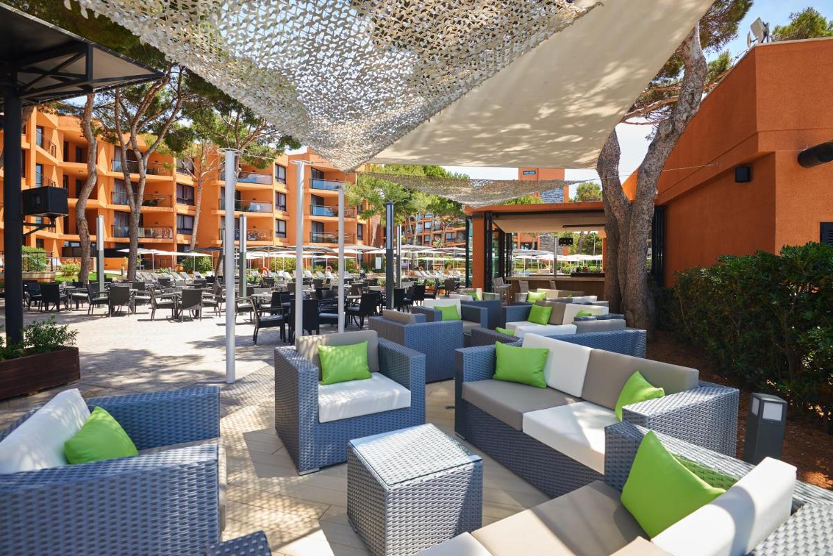 un patio al aire libre con mesas y sillas azules y blancas en Protur Turo Pins 4* SUP, en Cala Ratjada