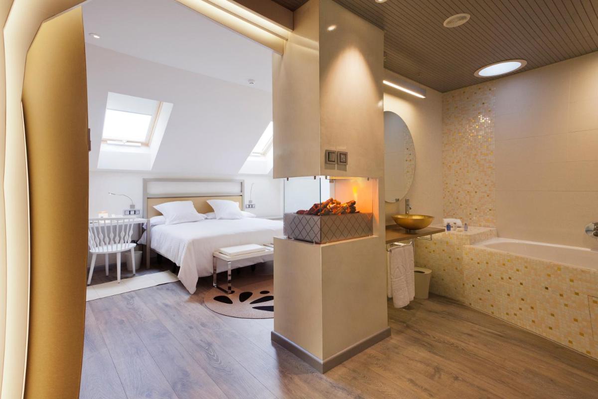 Un dormitorio con una cama y una bañera al lado de un baño. en Hotel & Spa Princesa Munia, en Oviedo