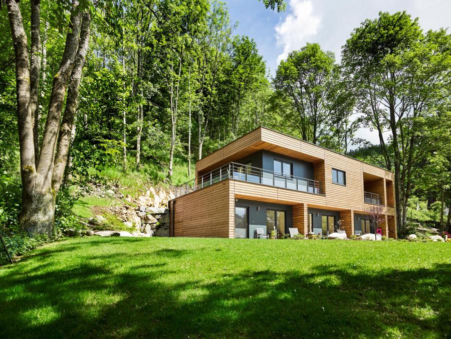 une maison dans les bois avec une pelouse verte dans l'établissement Logis Hôtel Restaurant De La Poste et SPA de Montagne, à Le Bonhomme