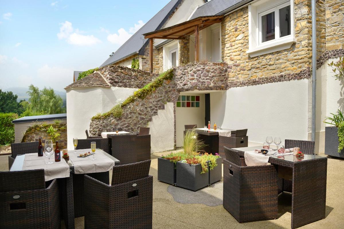 d'une terrasse avec des tables et des chaises. dans l'établissement Logis Hotel Spa Restaurant Au Site Normand, à Clécy