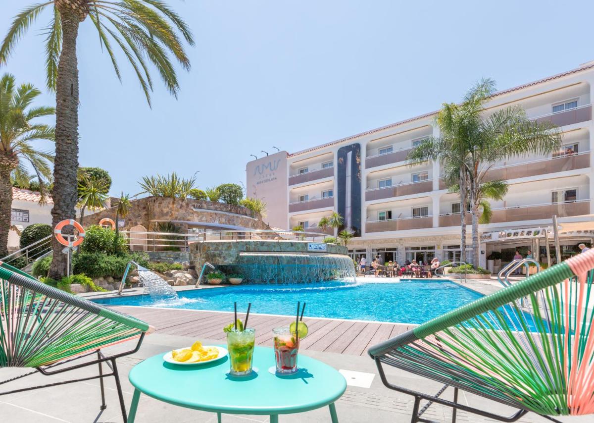 Una vista de una piscina con dos sillas y una mesa con bebidas. en Sumus Hotel Monteplaya & SPA 4Sup - Adults Only, en Malgrat de Mar