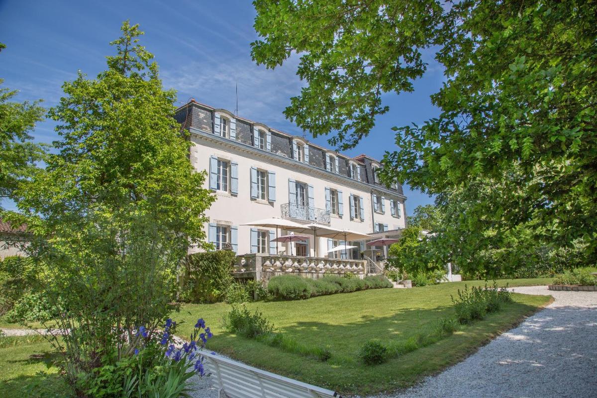 un grand bâtiment blanc avec une clôture devant lui dans l'établissement Logis Hôtel Restaurant Château Bellevue, à Cazaubon