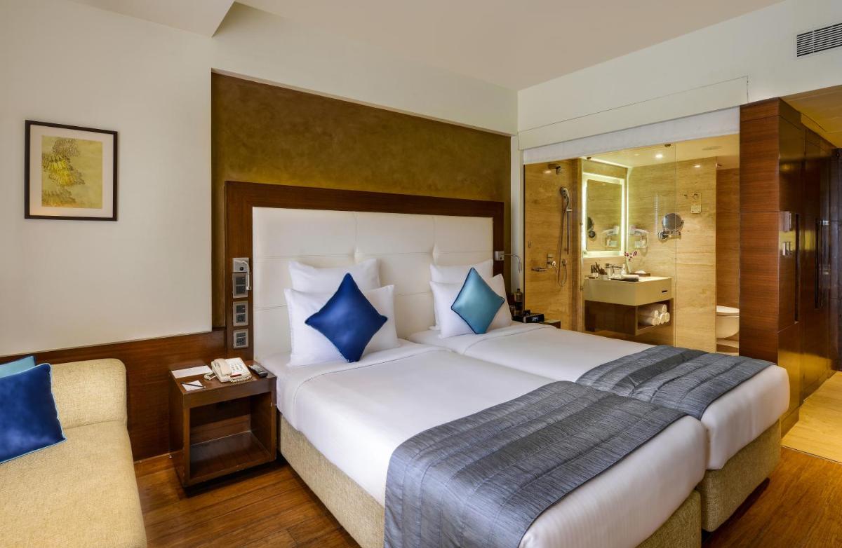 a hotel room with a large bed and a bathroom at Novotel Goa Candolim in Candolim a hotel room with a large bed and a bathroom at Novotel Goa Candolim in Candolim