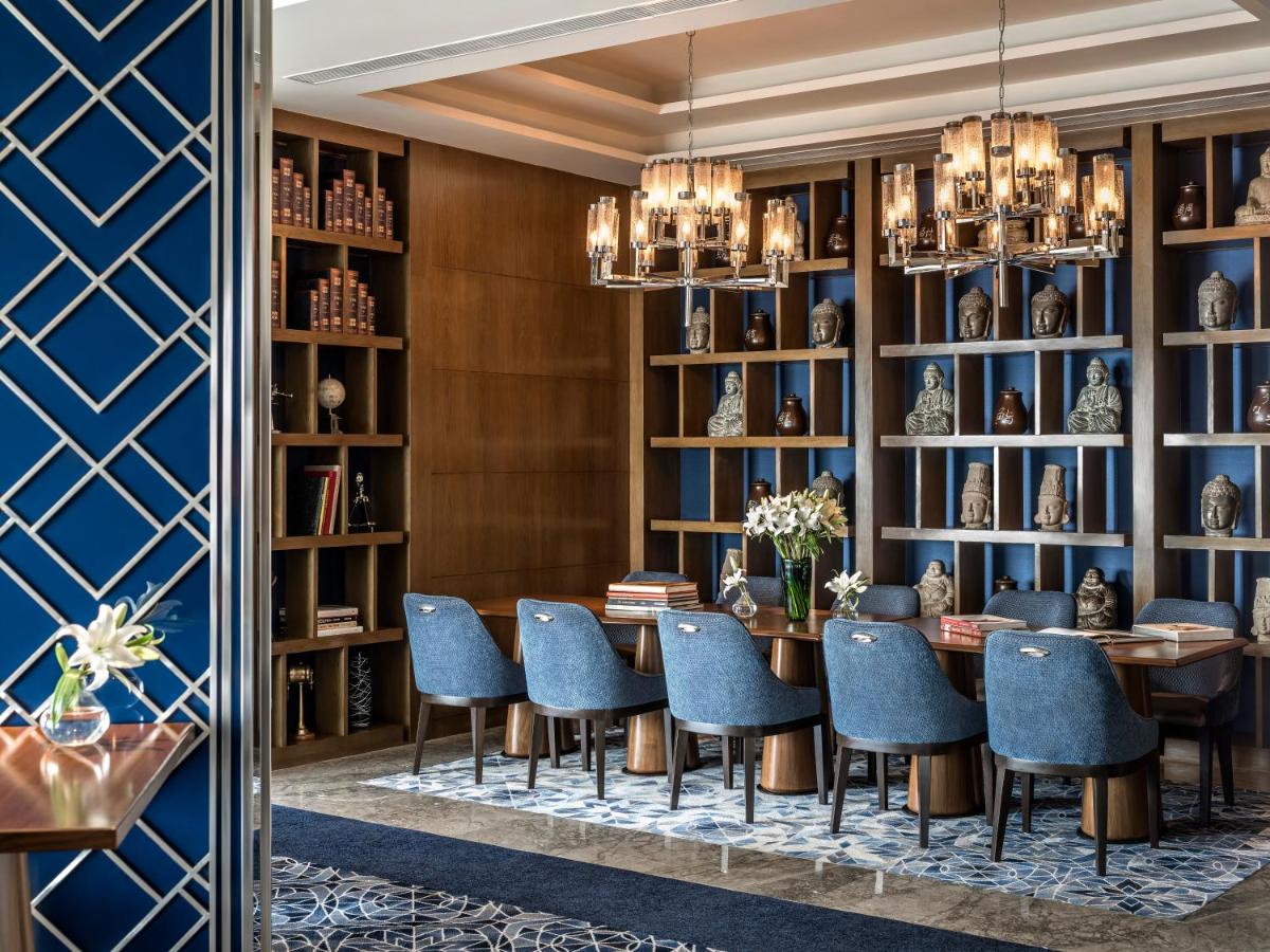 a dining room with blue chairs and a table and bookshelves at Shangri-La Eros New Delhi in New Delhi a dining room with blue chairs and a table and bookshelves at Shangri-La Eros New Delhi in New Delhi
